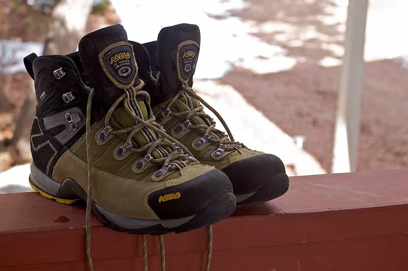 A pair of well-worn hiking boots resting on a railing