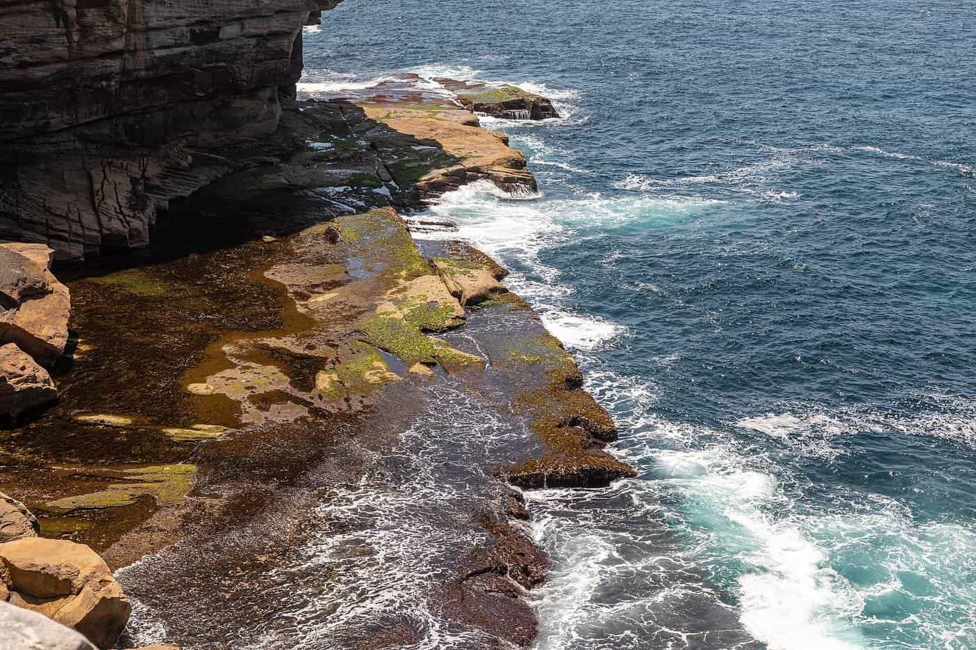 Ocean swell breaking against sandstone rock platforms below coastal cliffs